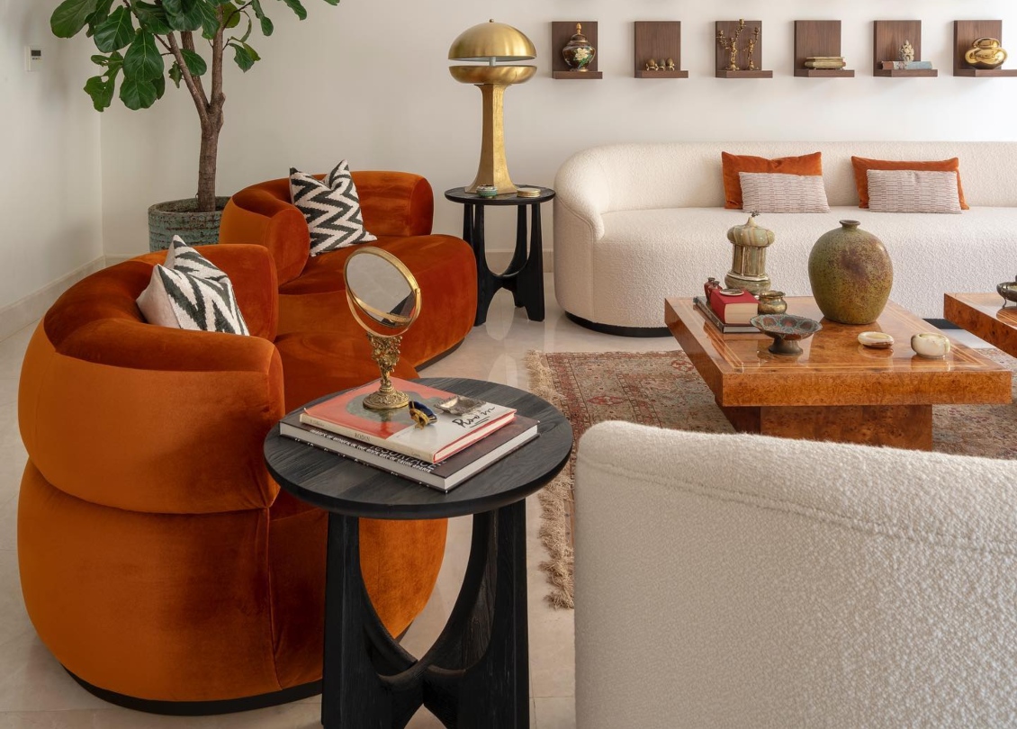 A Interiors design project in Saudi Arabia. The project has neutral colours contrasted with orange tones and gold. The armchairs are in orange and the sofa is in bouclé white.