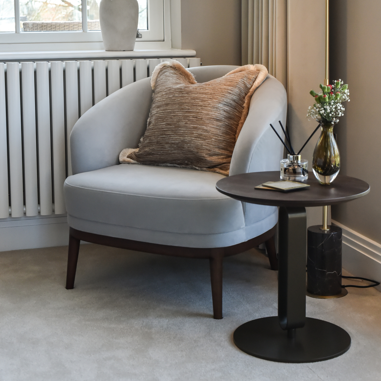 A modern grey armchair and a lamp sit together in a room, adding a touch of elegance to the decor in a master bedroom design.