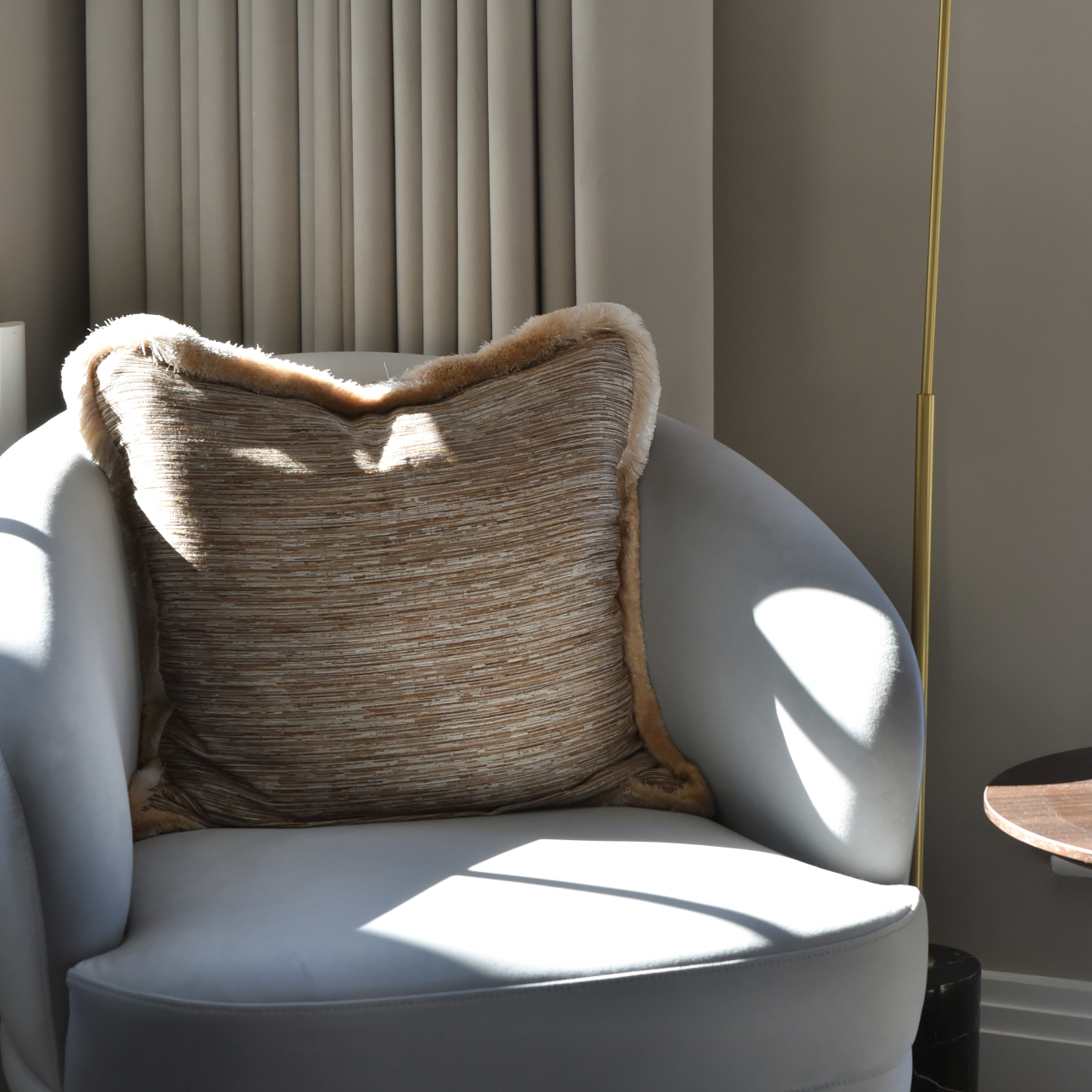 A comfortable armchair adorned with a pillow, next to a lamp, set in a stylish master bedroom design.