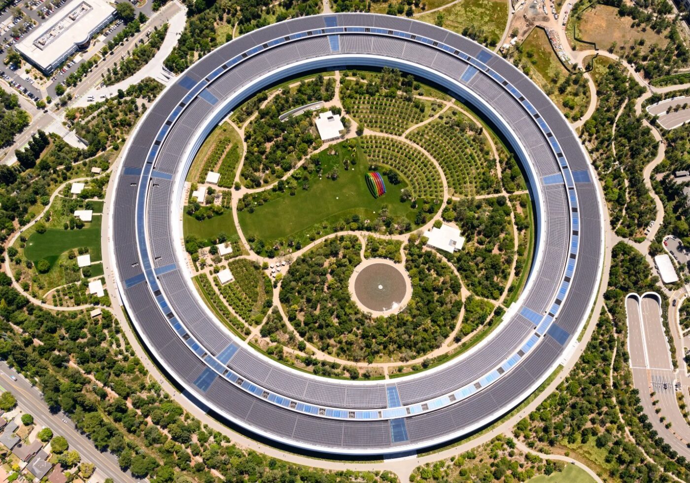 Apple Park by the architecture firm Foster + Partners. The building is circular with a garden in the middle.