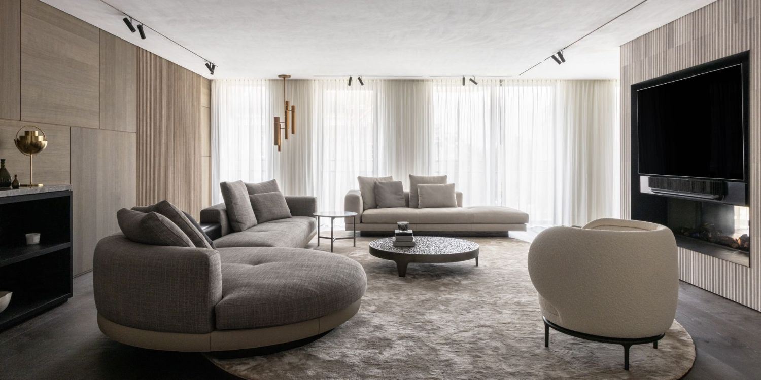 Living room in neutral tones and white and grey accents. With a round sofa and a white sofa and a white armchair. From the Kolenik Design, one of the best interior designers in the Netherlands.