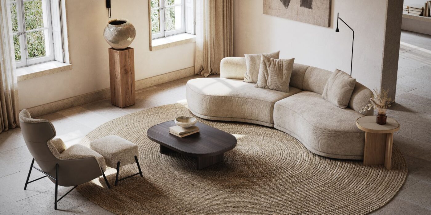 Blog Featured Image - 2026-03-10T172131.507 Sophisticated living room with a beige curved sofa, armchair, and dark coffee table on a large circular jute rug. Warm tones create an inviting atmosphere.