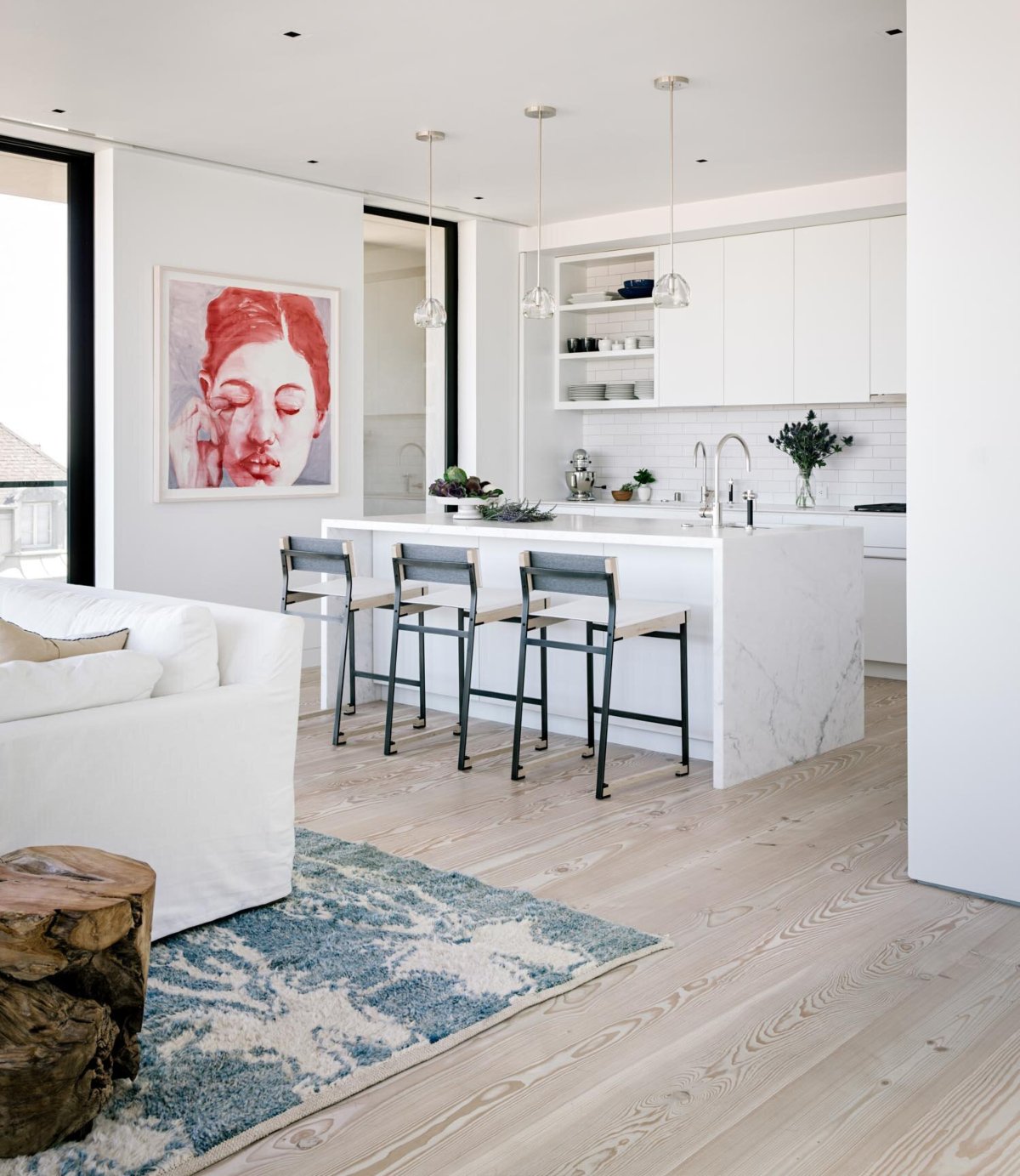 Butterfly House project by Shawback Design. The kitchen has a marble counter and three counter chairs in white and black steel.