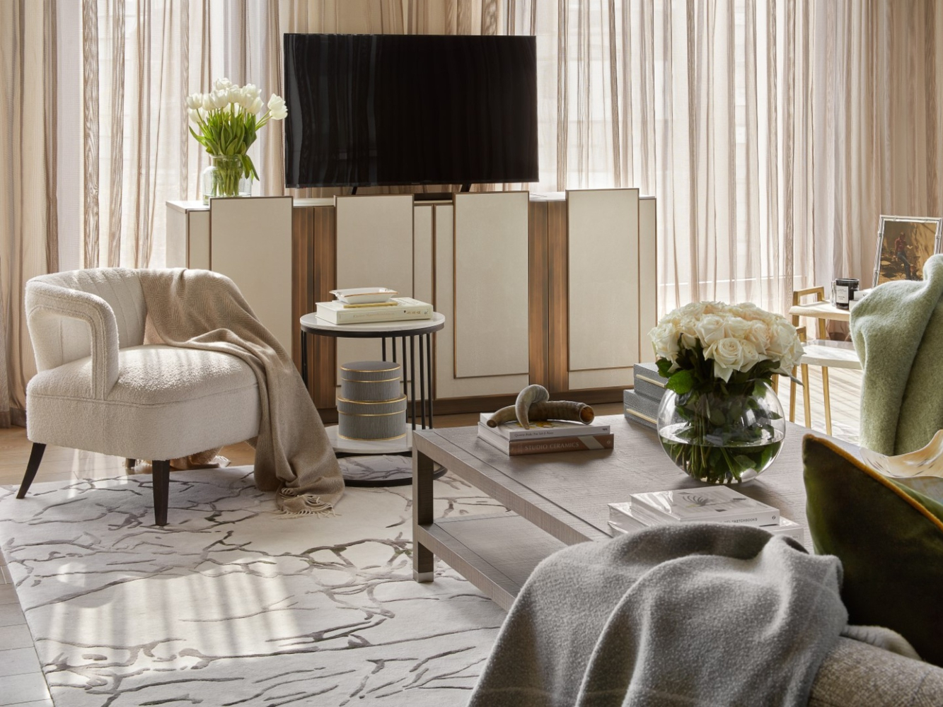 Living room project by Celine Interior design. With neutral tones and a armchair with boucle fabric. With a tv cabinet in white and gold accents.