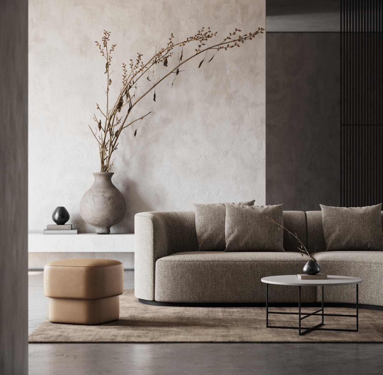 Living room with a comfortable sofa, a bege pouf and a round coffee table. The main colours are neutral and browns. It has a vase in the back of the room.