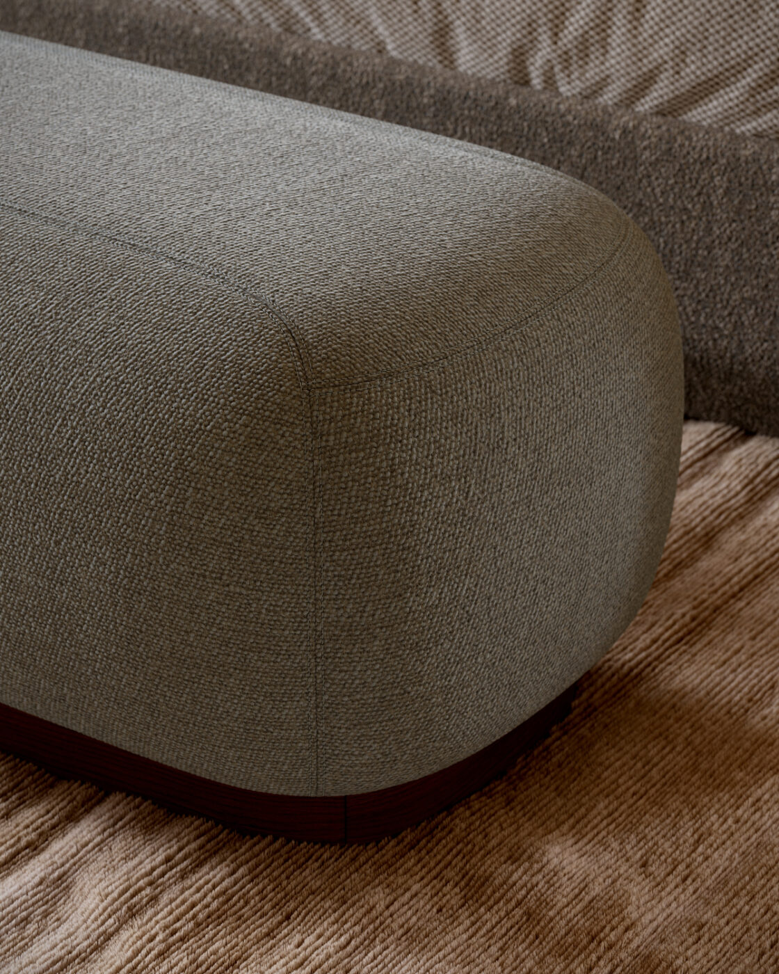 A soft blue Claire Bench is placed on a rich wooden floor, creating a comfortable and modern look in the room.