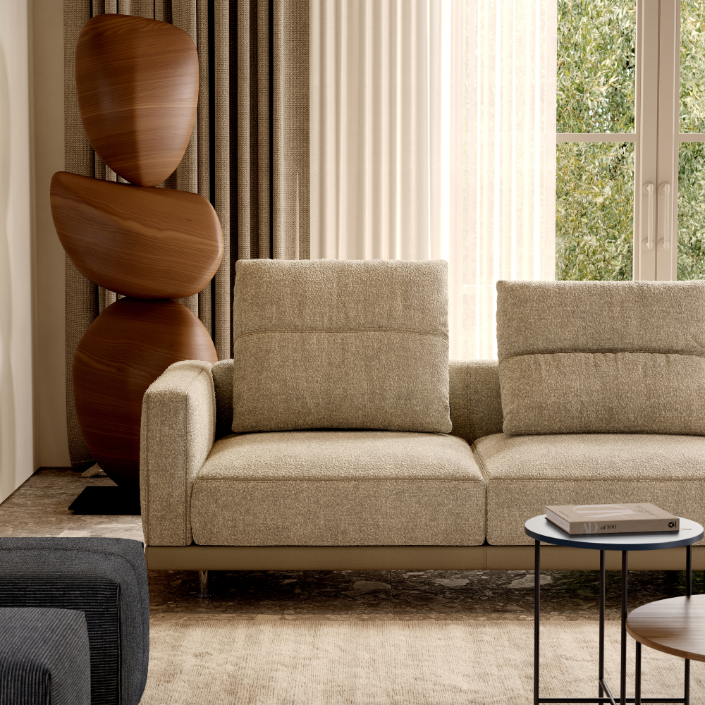 Upholstered sofa in light beige fabric in a living room in front of a big window.
