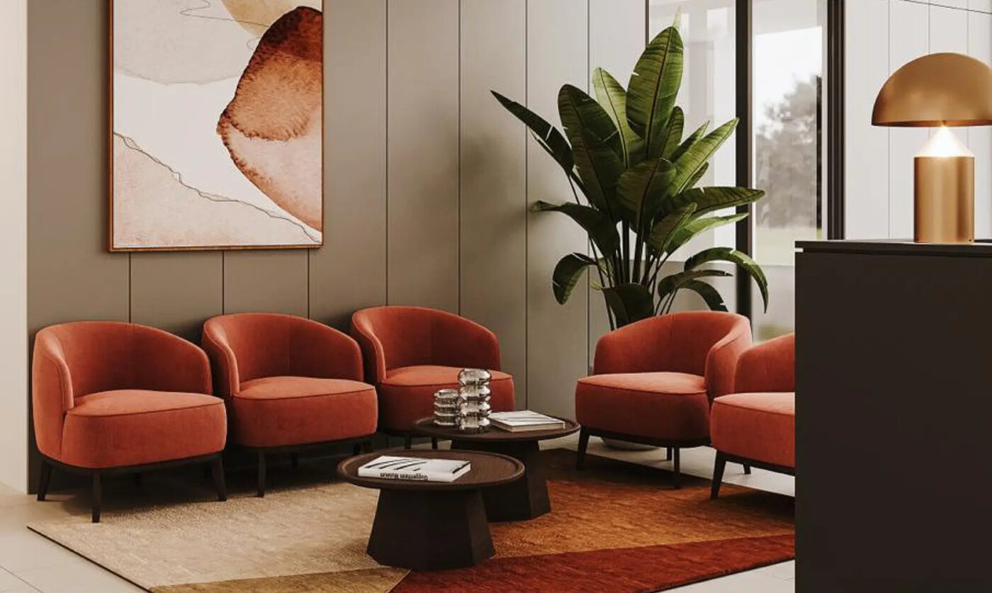 lobby project with five armchairs in peach colour and two wood coffee tables at the centre. With a vase with a green plant in the back and a piece of art in neutral tones. On the floor is a rug in terracotta and neutral tones.