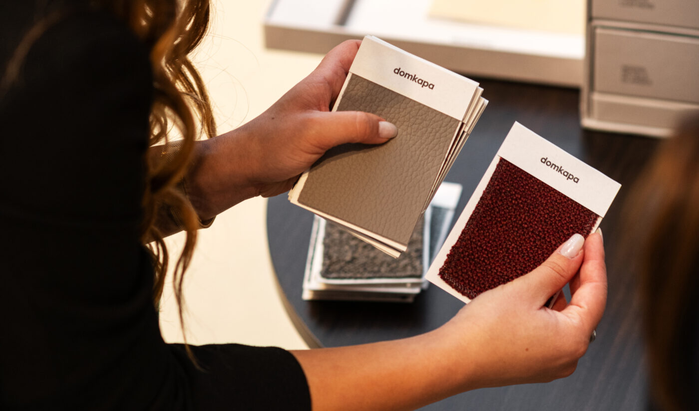 A woman holds up a pair of fabric swatches, showcasing their vivid designs and playful colour and texture combinations. About furniture colours and fabrics