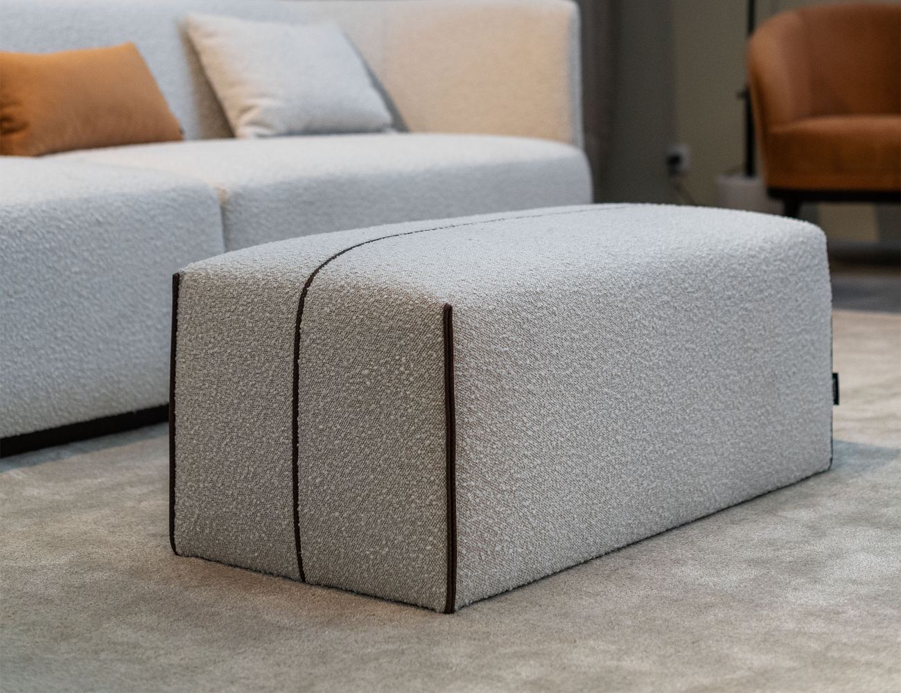 A white pouf placed in front of a comfortable sofa, enhancing the inviting atmosphere of the living space. The pouf is in bouclé, one of the trending materials.