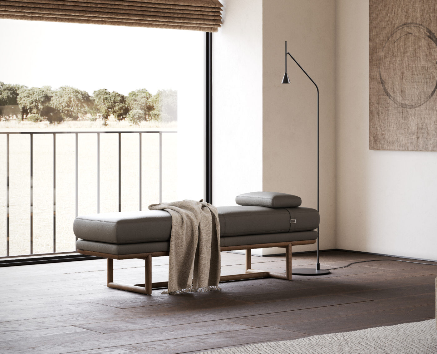 Minimalist interior with a modern gray upholstered bench, draped with a beige blanket, and a sleek floor lamp nearby. Large window offers a view of a sunny, tree-lined field. Neutral tones and clean lines create a serene, contemporary atmosphere.