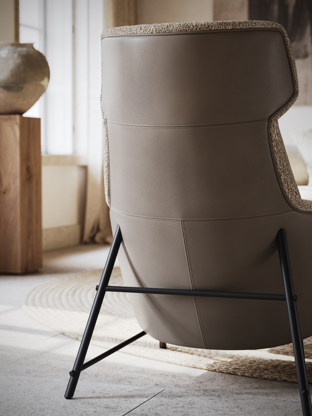 Back of an armchair upholstered in brown leather and with black steel legs.