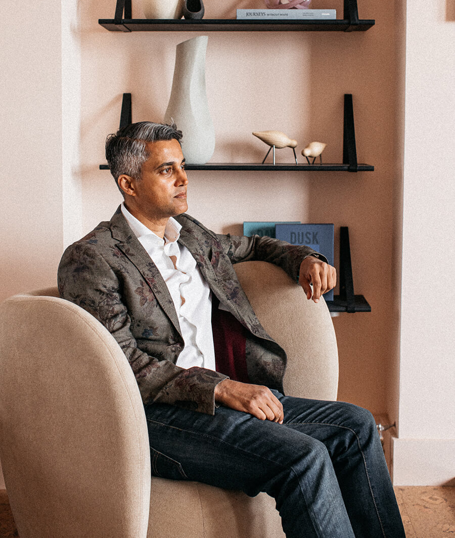 Imraan Ismail, the interior designer behind the Port Hotel project. This photo was taked in the restaurant of the hotel and it has pink tones and an armchair in neutral velvet.