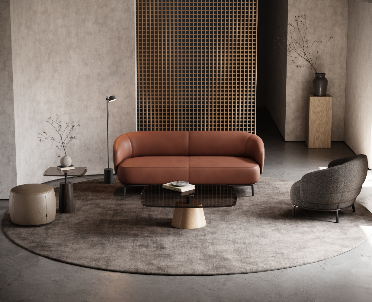 Living room with a leather sofa in red and an armchair in boucle. It has a pouf in light brown leather and a coffee table and side table, both in glass and wood. Custom upholstery on the sofa and armchair.