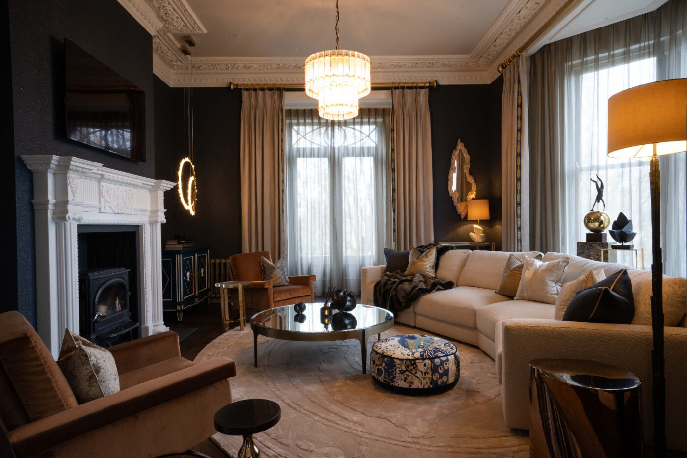 Kris Turnbull Studios project with Edward A warm living room scene with a fireplace, inviting modular sofa, and elegant chairs for seating and comfort.