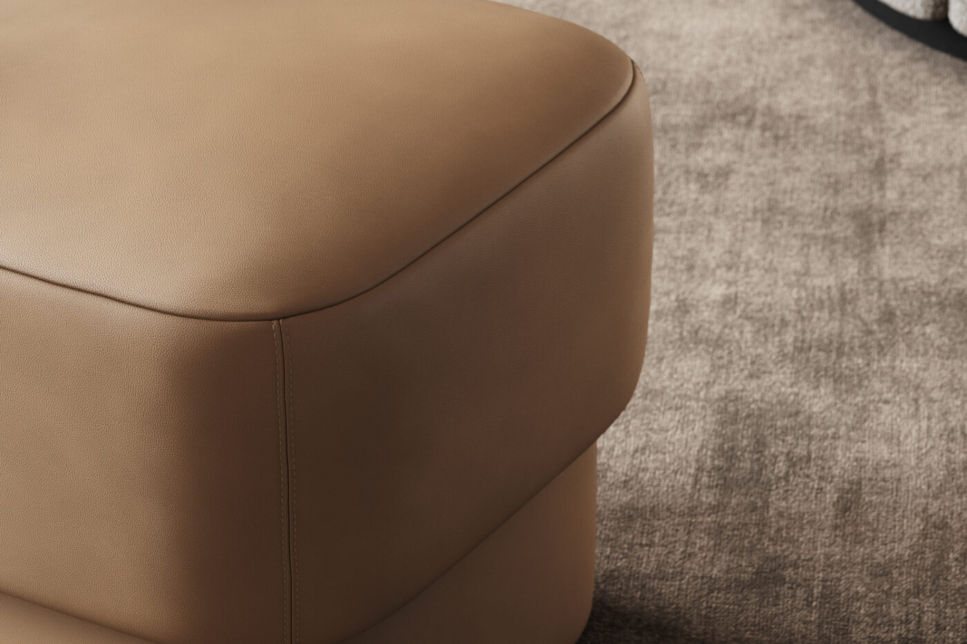 Detailed close-up of a tan leather pouf, highlighting its smooth surface and elegant design. With invisible stitching.