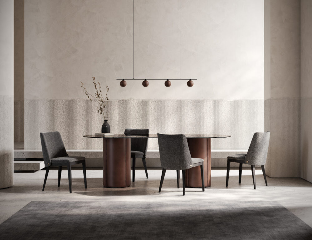 dining chair with four chairs in grey fabric and wood base. The dining table is oval and has two legs upholstered in brown leather and the top in glass.