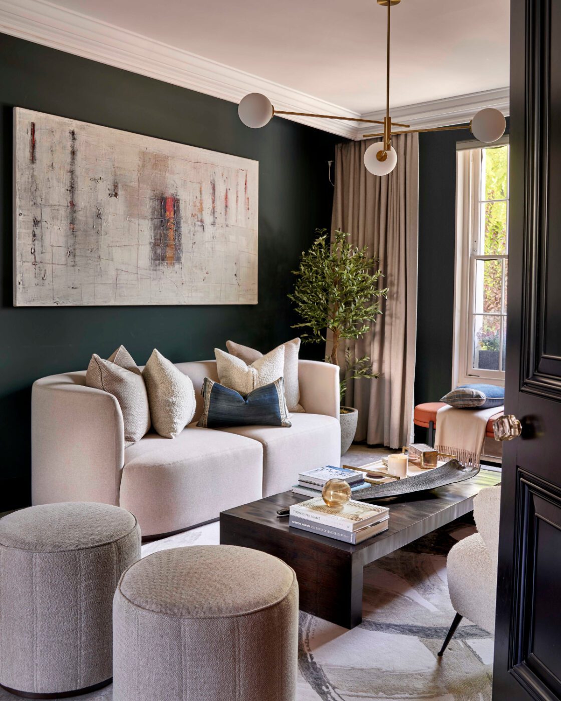 Low Pouf at a The Stylish Friend project A cosy living room with rich dark green walls and sleek light furniture, offering a contemporary and elegant design. A The Stylish Friend project.