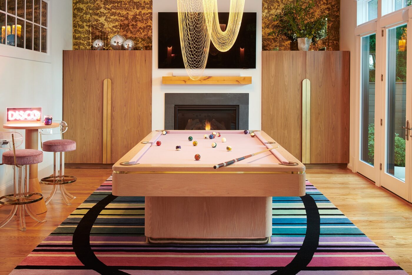 Colourful game room in the Mid Atlantic project. It has pink bar chairs and a pink 8 ball table. Also has a very colourful carpet.