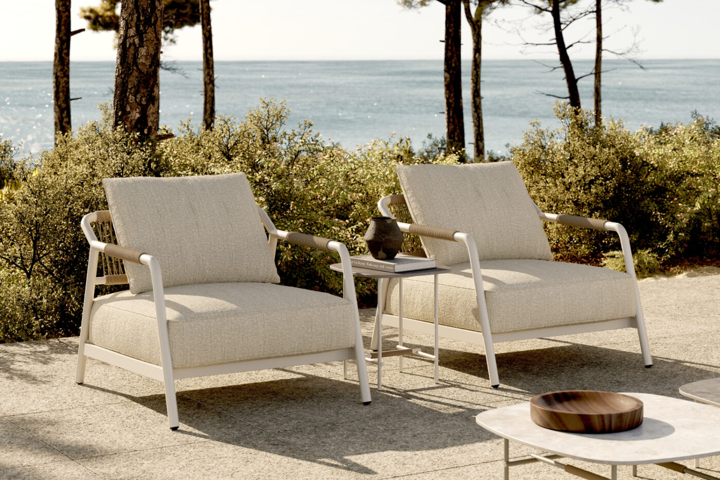 Two armchairs and a table set on a patio, with a beautiful ocean view nearby. Outdoor style by Domkapa.