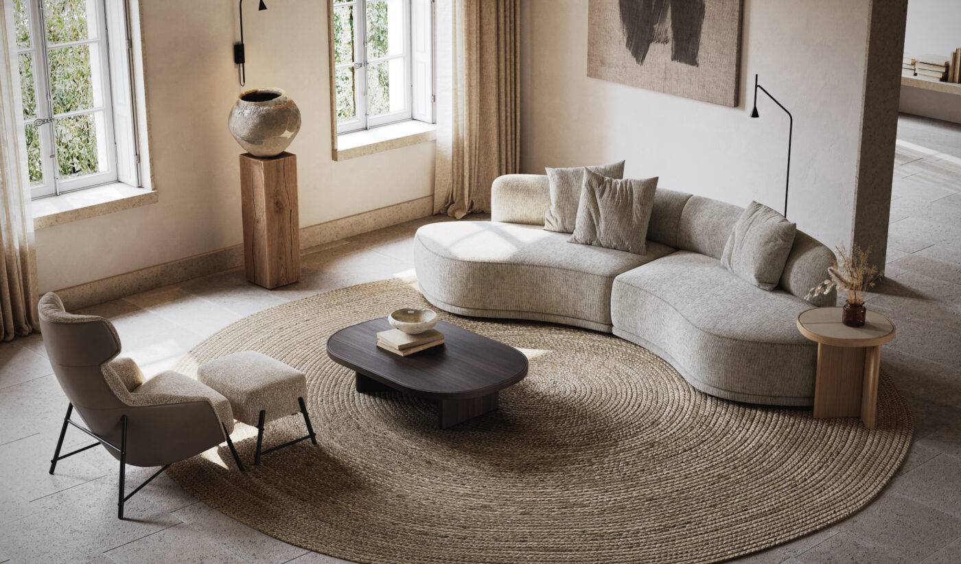 A modern living room with a curved beige sofa, round coffee table, and a high-backed chair with an ottoman. Large windows let in natural light, and a textured abstract artwork hangs on the wall. Neutral tones and a woven rug complete the serene look.