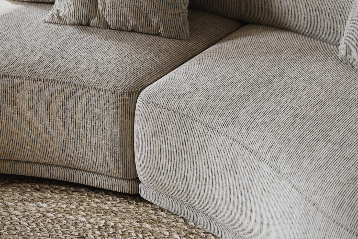 Curved sofa in beige fabric with the blanket stitching.