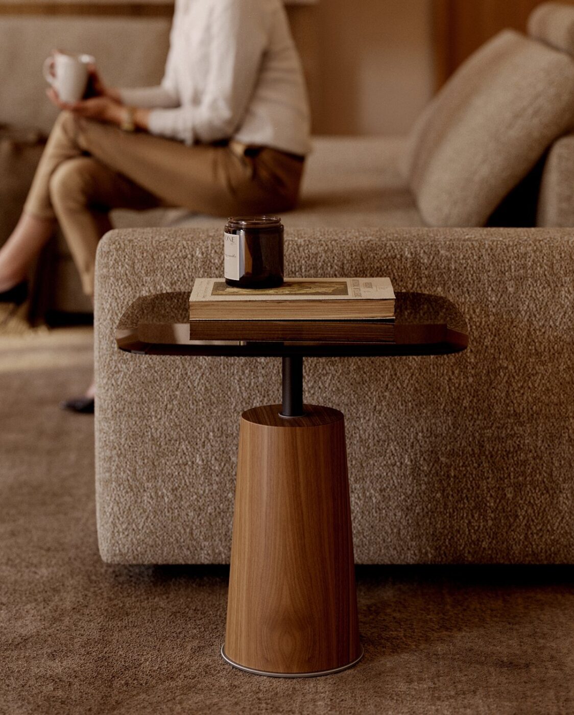 Panton side table in wood and glass beside Edward sofa. The side table has a book and a candle on the top of the glass.