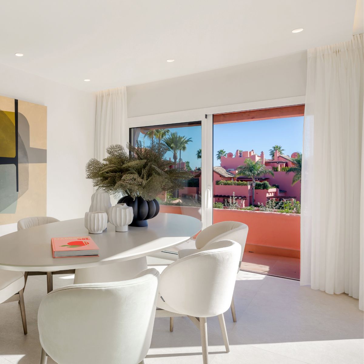 Project with Norah by Maite de la Rosa Bright dining room showcasing white chairs and a prominent large painting, creating a stylish atmosphere.