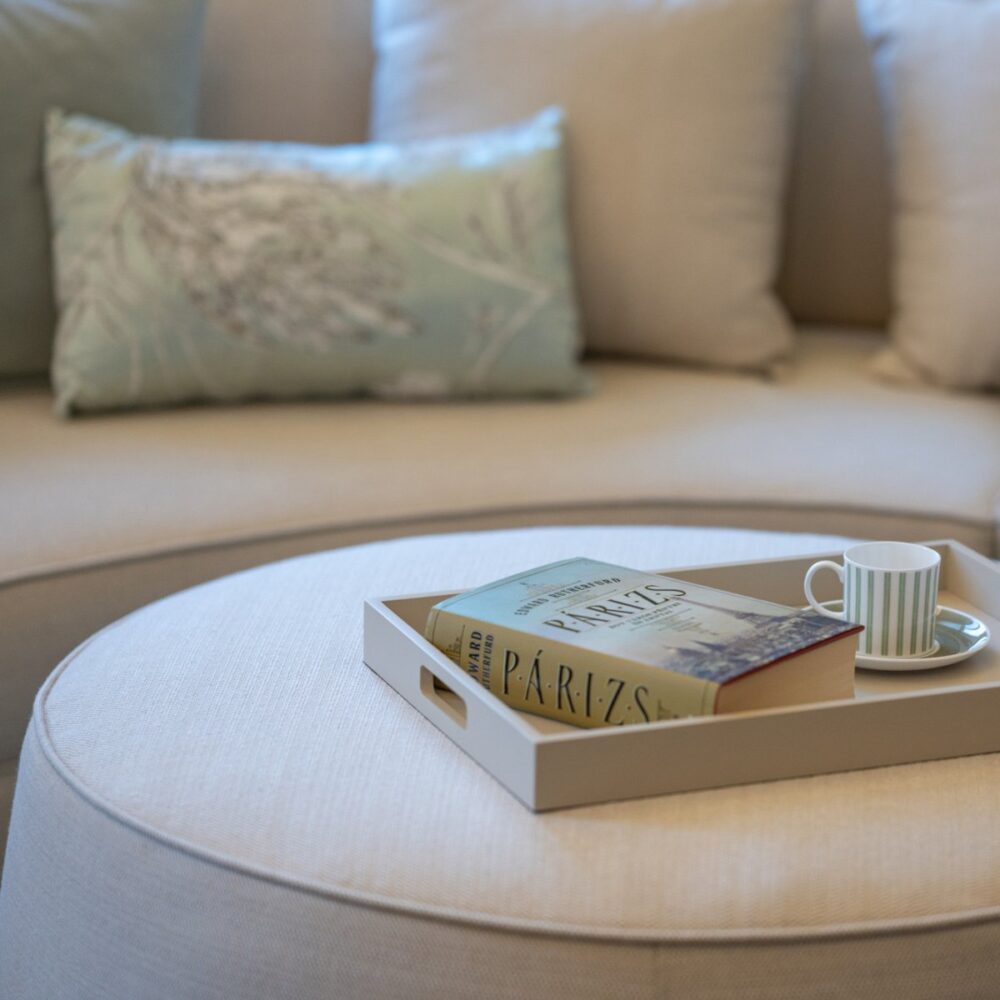 Rachel pouf in white with a book and a coffee cup on top.