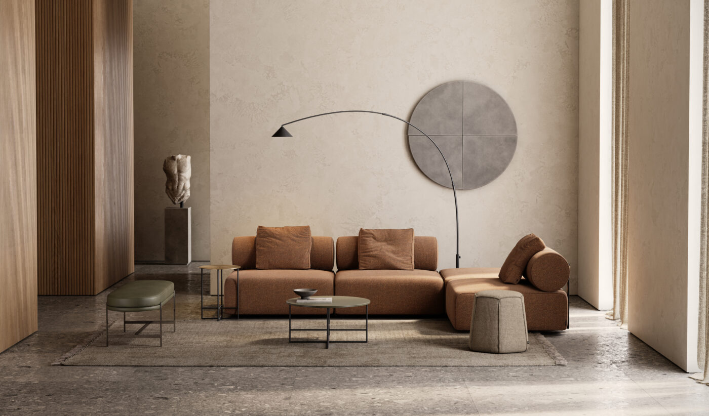 A modern living room with a terracotta sectional sofa, a round coffee table, and a tall arc floor lamp. A large circular wall art piece and a sculpted bust on a pedestal decorate the space. Natural light streams through a tall window. Perfect for winter. Interior Design Trends For Winter