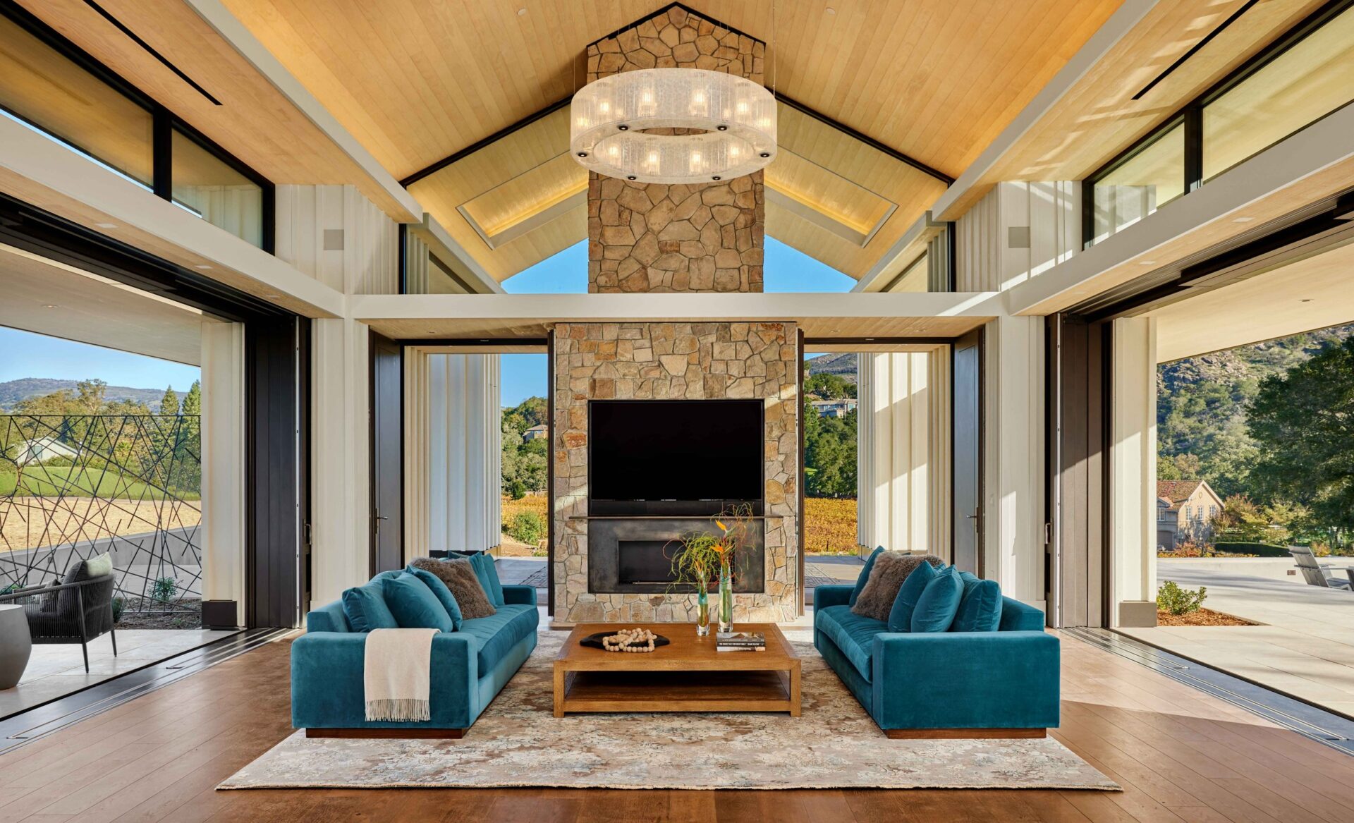 Trilogy Project by Shawback Design with a living room with blue sofas and a fireplace made in stone. It is an open space with an abundance of natural light.