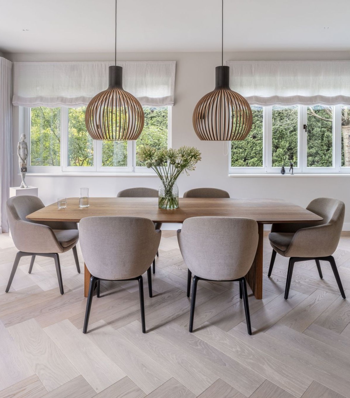 dining room with neutral toned dinig chairs and a wooden dining table. With two lighting pieces in wood.