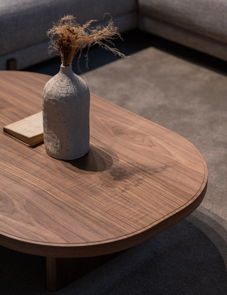 A wooden coffee table adorned with a vase, showcasing a simple yet elegant design. Sustainable wood is one of the 5 trending materials for 2025.