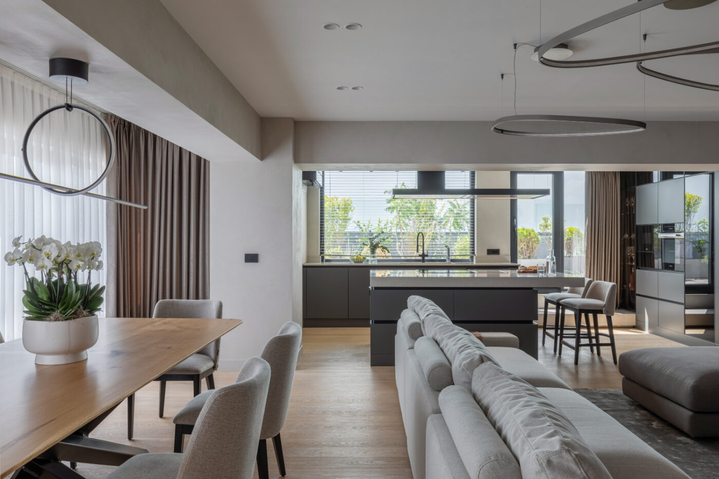 A contemporary apartment interior with a dining table and chairs, counter chairs and a modular sofa creating a warm and welcoming dining space.