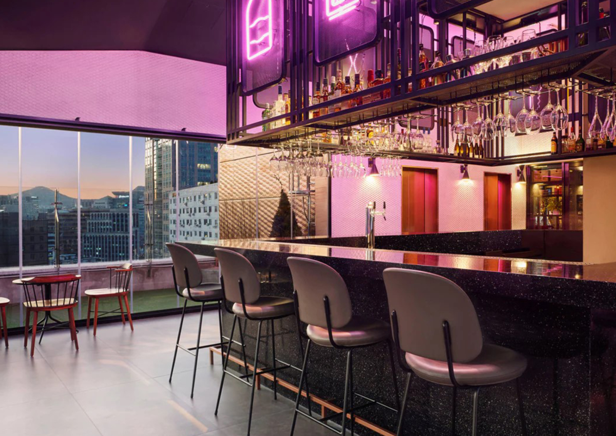 A vibrant bar scene in Asia with purple neon lighting and modern chairs, creating a lively atmosphere.