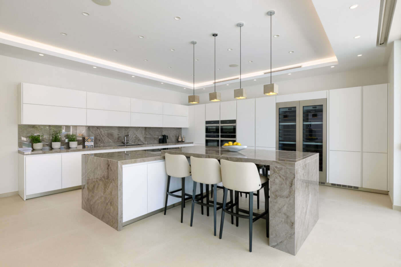 Contemporary kitchen with polished marble countertops and bright white cabinets forming angular lines, emphasising a stylish and spacious atmosphere.