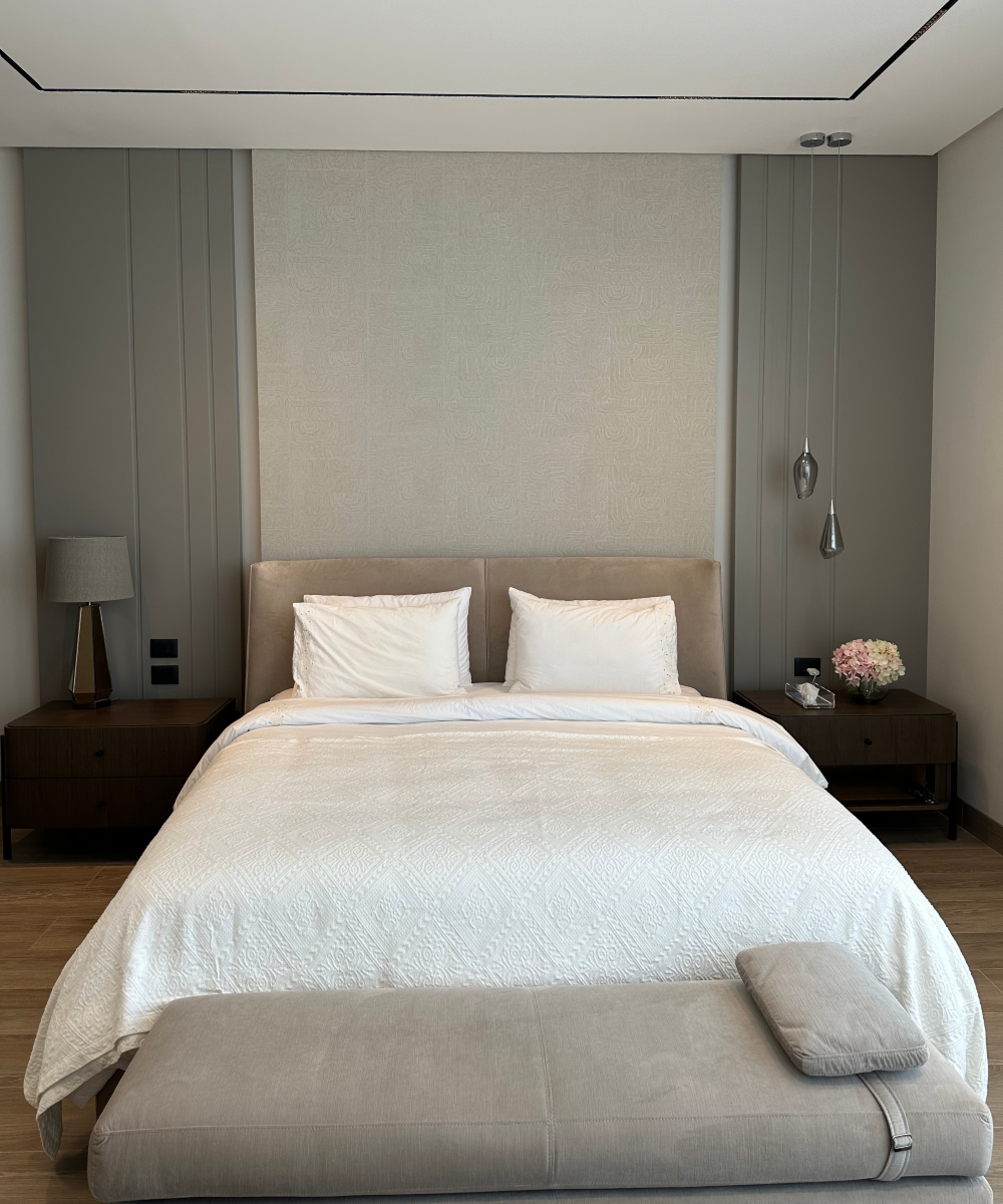 A cosy bed adorned with a white comforter and a beige headboard, creating a serene atmosphere. A project by Ecth & Notch designs.