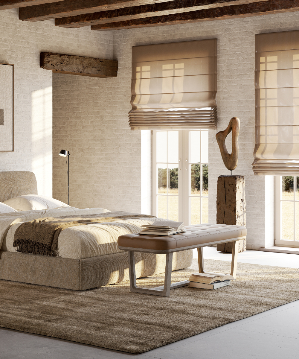 A cosy bedroom featuring a bed, a bedside table, a bench in front of the bed, and a window letting in natural light. Bedroom essentials.