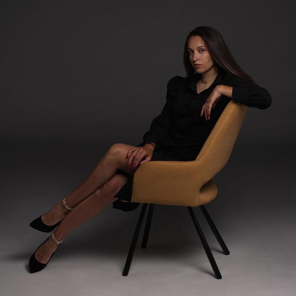 best interior designers in Austria by Domkapa (1) A Anna Kosari wearing a black dress is seated on a chair, showcasing a stylish and sophisticated appearance.