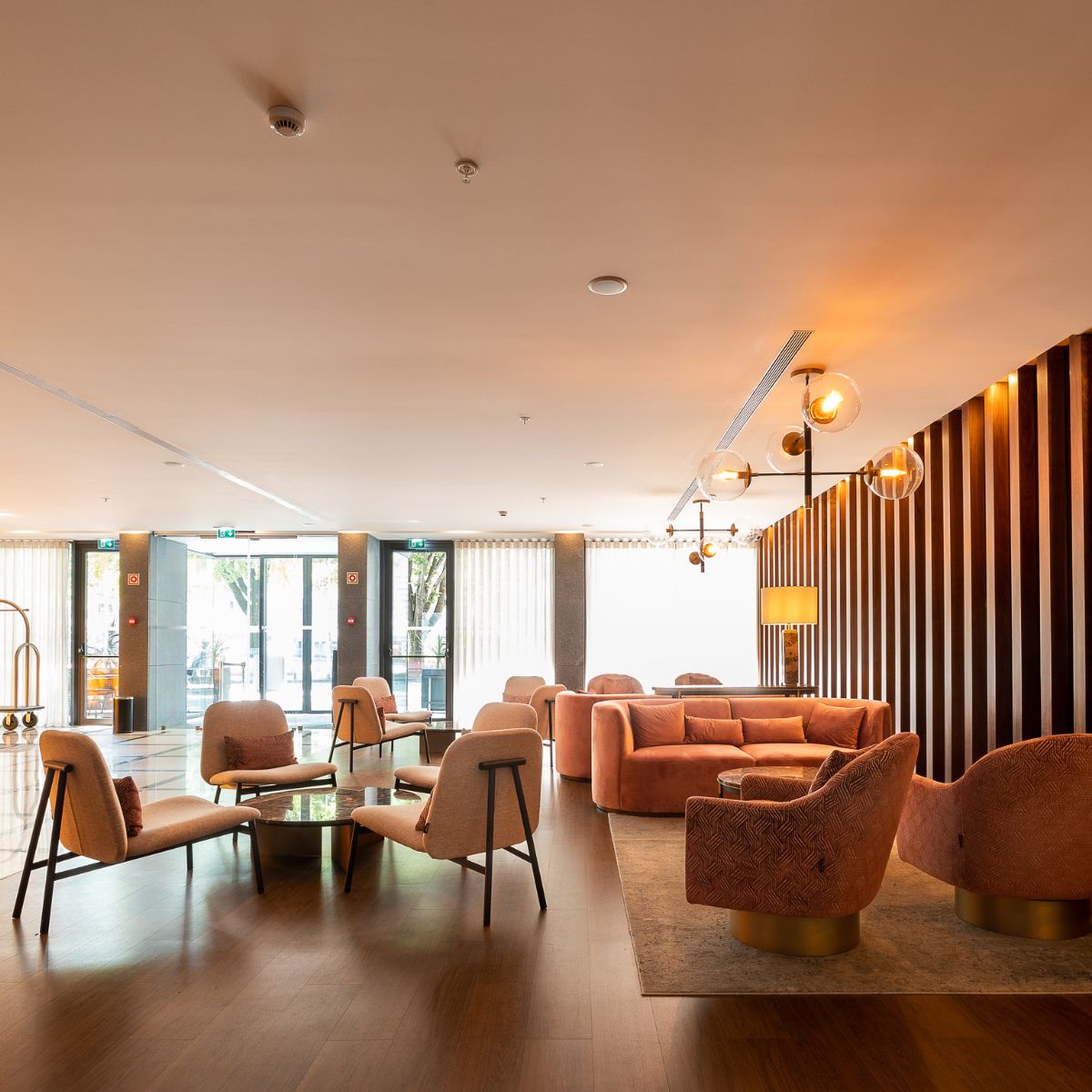 blog article about com vs house fabric by domkapa (1) Hotel lobby featuring a large wooden wall, elegant seating, and decorative lighting, creating a welcoming atmosphere.