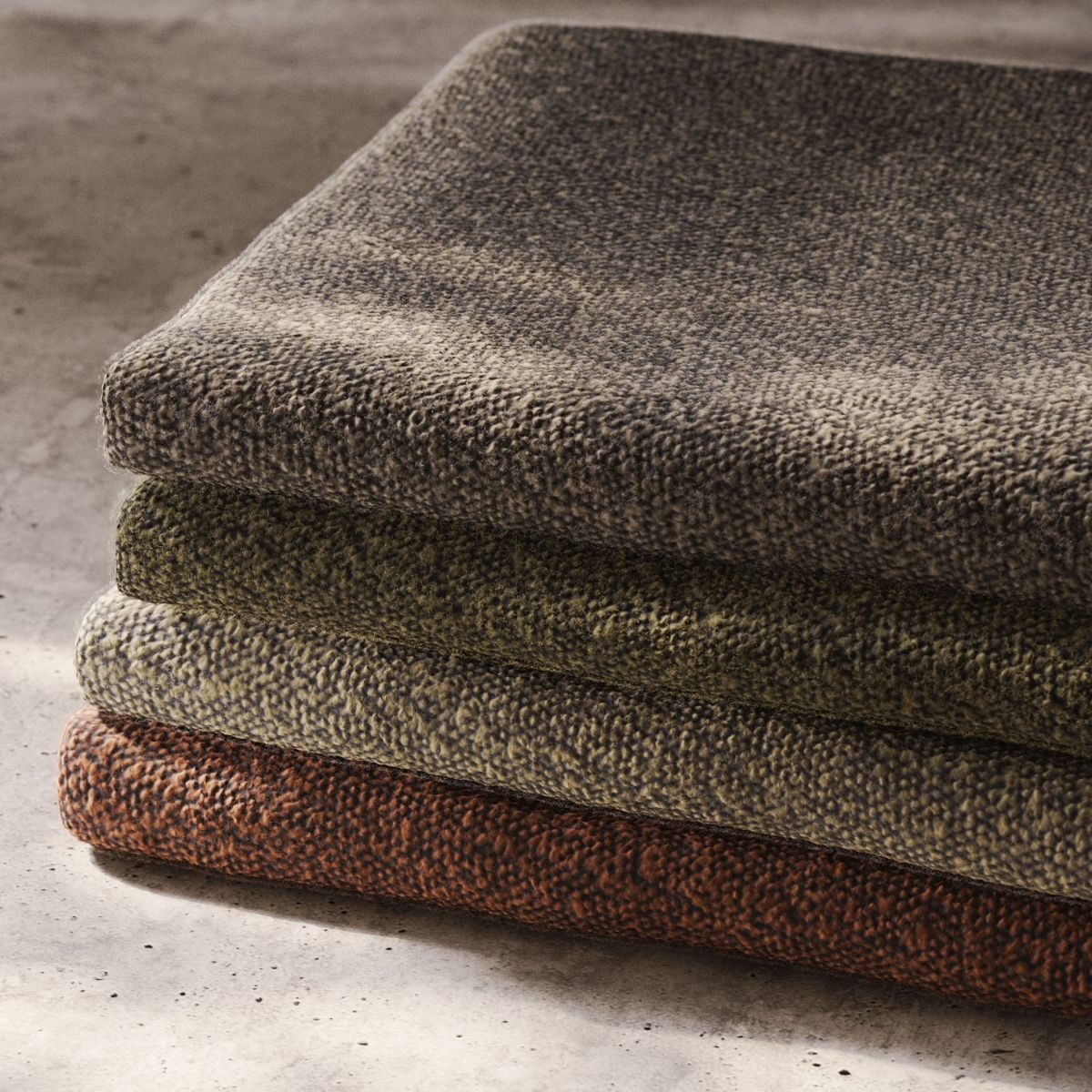 blog article about com vs house fabric by domkapa (2) A stack of four neatly folded fabric swateches resting on a concrete floor. COM vs. house fabric