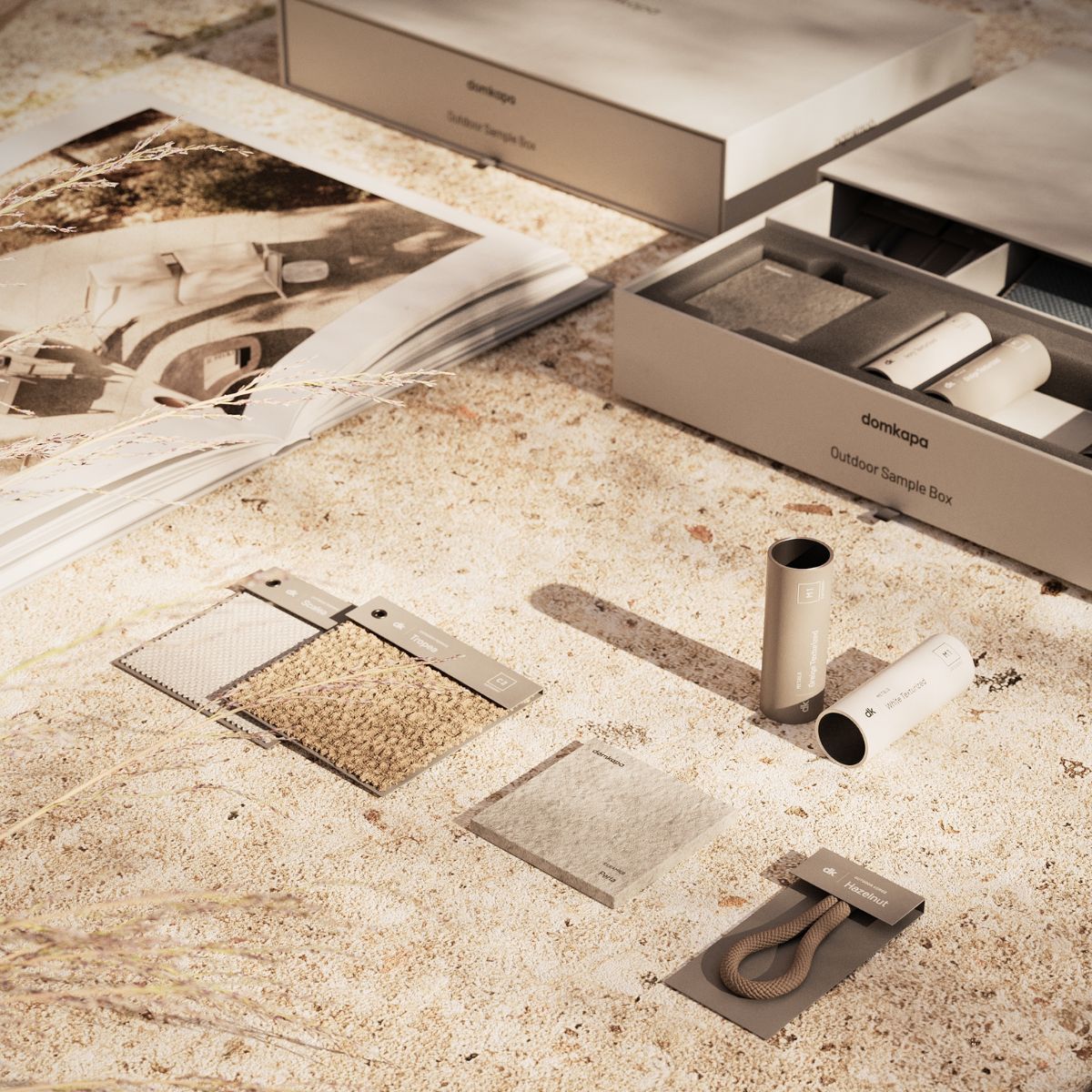 blog article about outdoor upholstery by domkapa (5) On an sandy surface, there is a catalogue, fabric swatches and a pair of metal samples neatly placed.