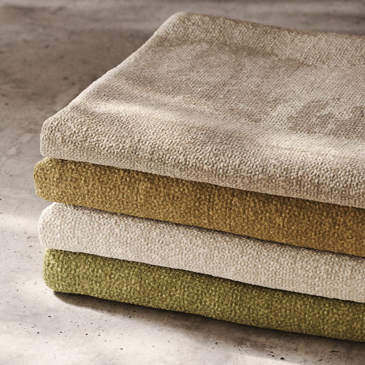 blog article about outdoor upholstery by domkapa (6) A colourful stack of swatches, displaying a variety of hues and textures or outdoor upholstery, neatly folded for organisation.