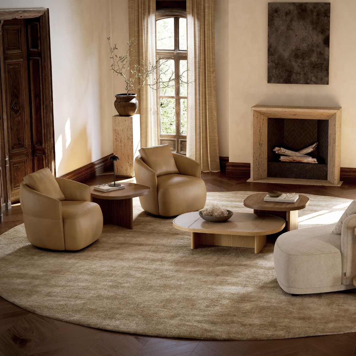 danish interior design (2) Cosy living room with beige tones: two leather armchairs, round tables, and a soft rug. A rustic fireplace and a tall window add warmth and elegance.