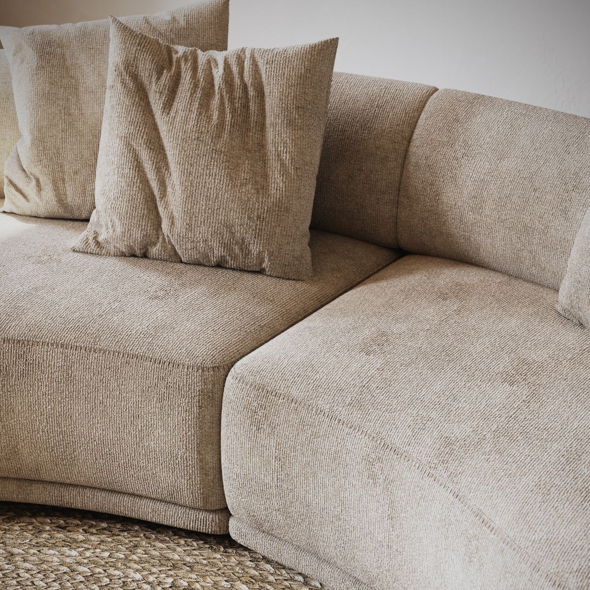 danish interior design (5) Beige, textured modular sofa with soft cushions on a woven rug. The setting appears cosy and inviting, emphasising comfort and warmth.