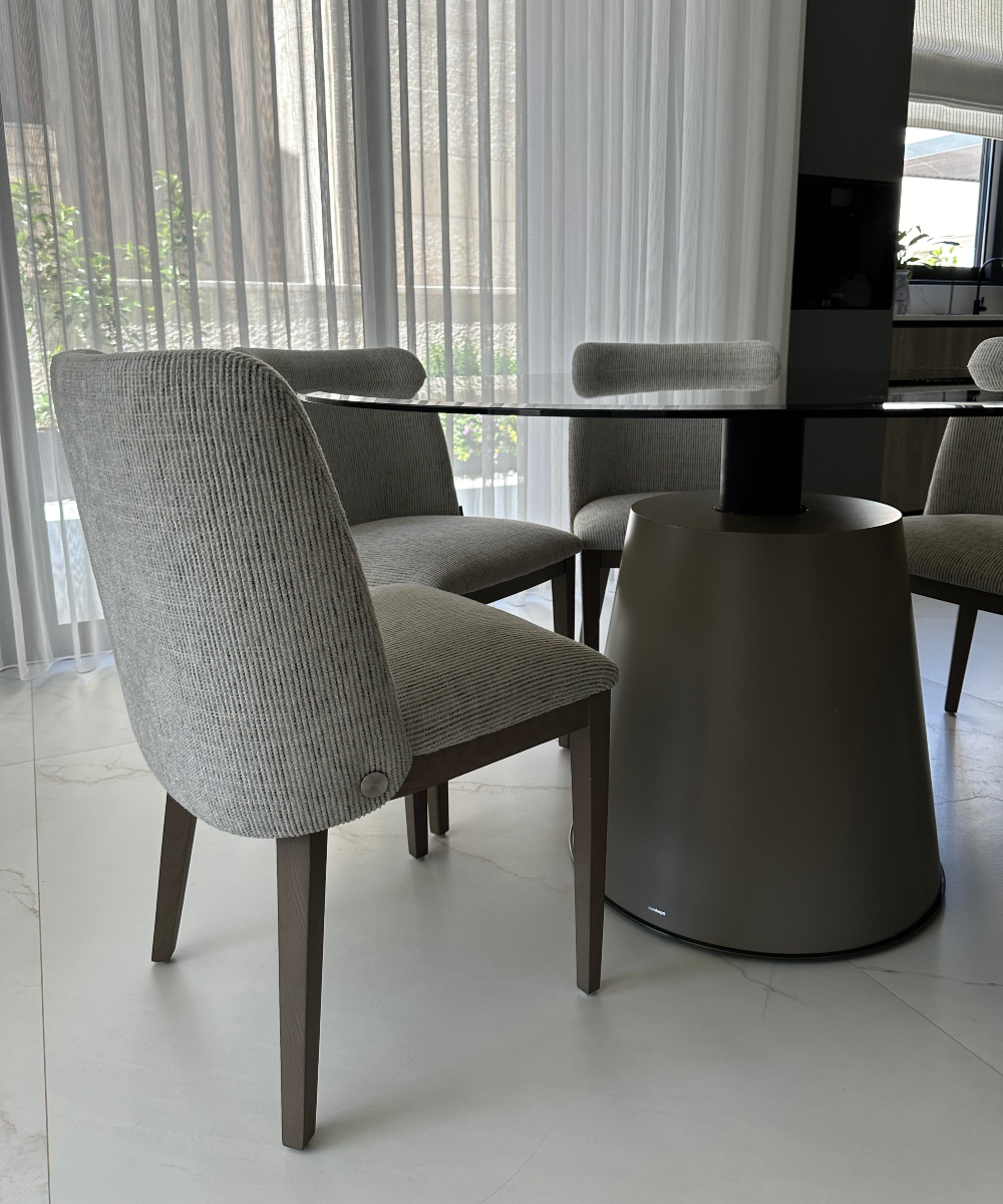 A round table featuring a glass surface, with four dining chairs positioned around it in a stylish setting. By Etch & Notch Designs.