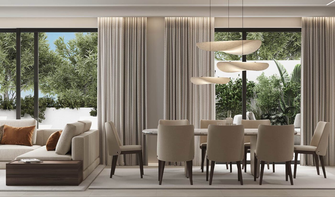 dining room by rental 12 A modern dining and living room with beige dining chairs, a table and a sofa. Large windows reveal lush greenery. Elegant hanging lights add a soft ambience.
