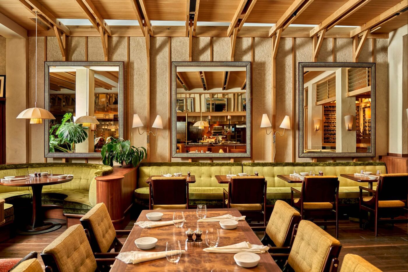 dovetale restaurant london Elegant restaurant interior featuring green upholstered seating, wooden tables set with white dishware, and large mirrors reflecting a warm ambiance.