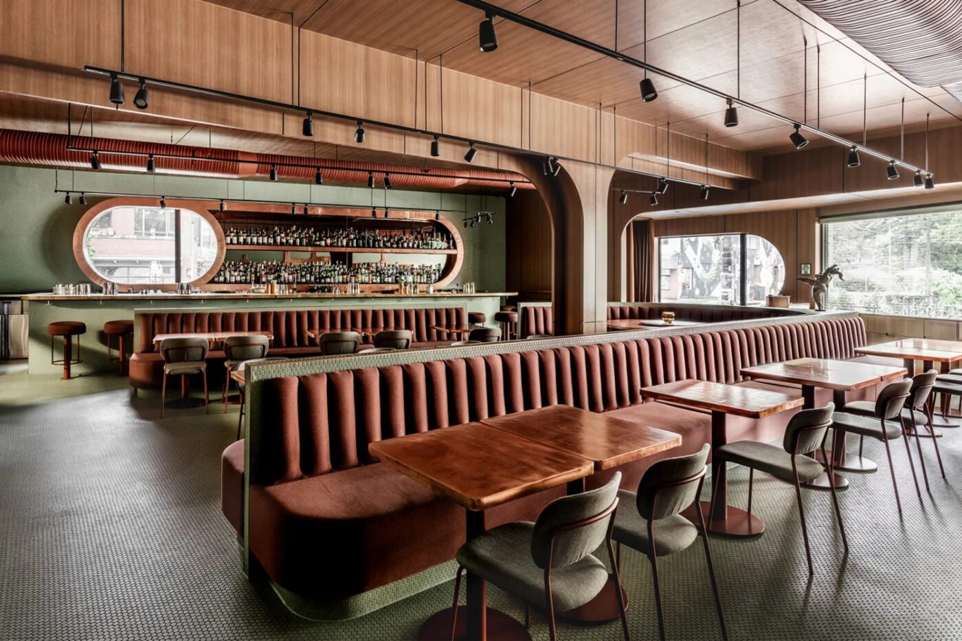 esrawe studio project Stylish, modern restaurant interior with wooden panelling, long upholstered banquettes, round tables, and a sleek bar with shelves of bottles. Cosy and inviting. Designed by one of the best mexican interior designers.