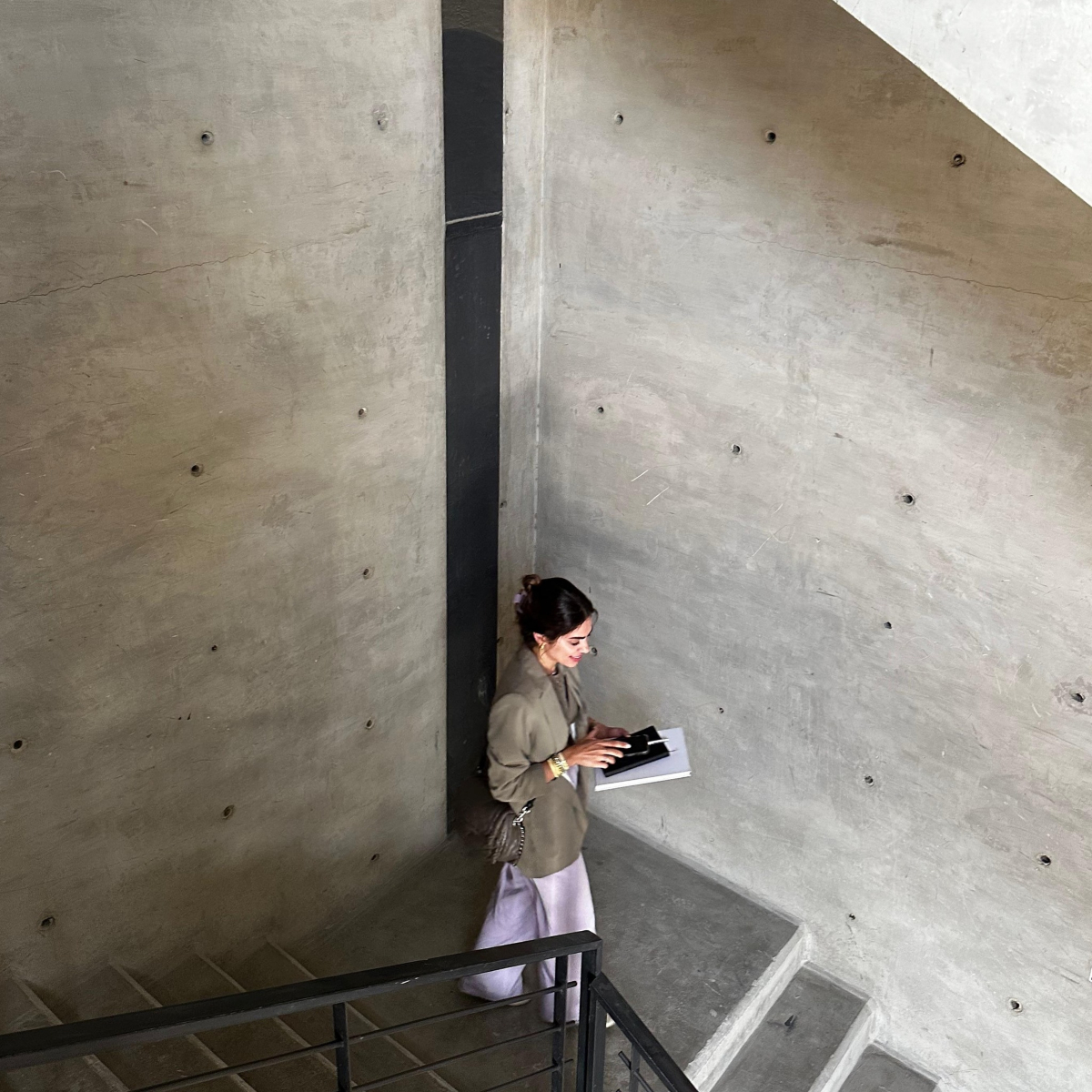 Noor from Etch & Notch Designs stands on the stairs of a building, looking thoughtfully into the distance.